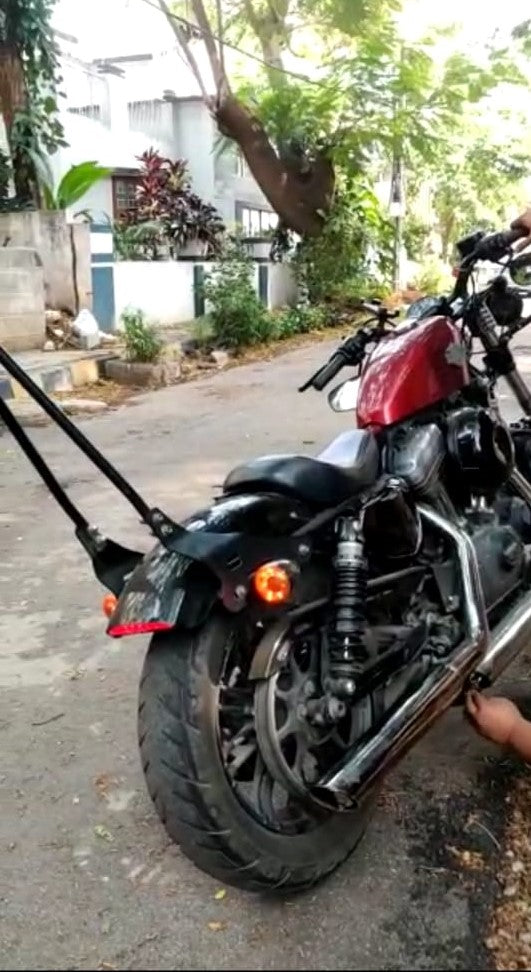 Hands fitting a DB killer insert into the exhaust outlet of a motorcycle