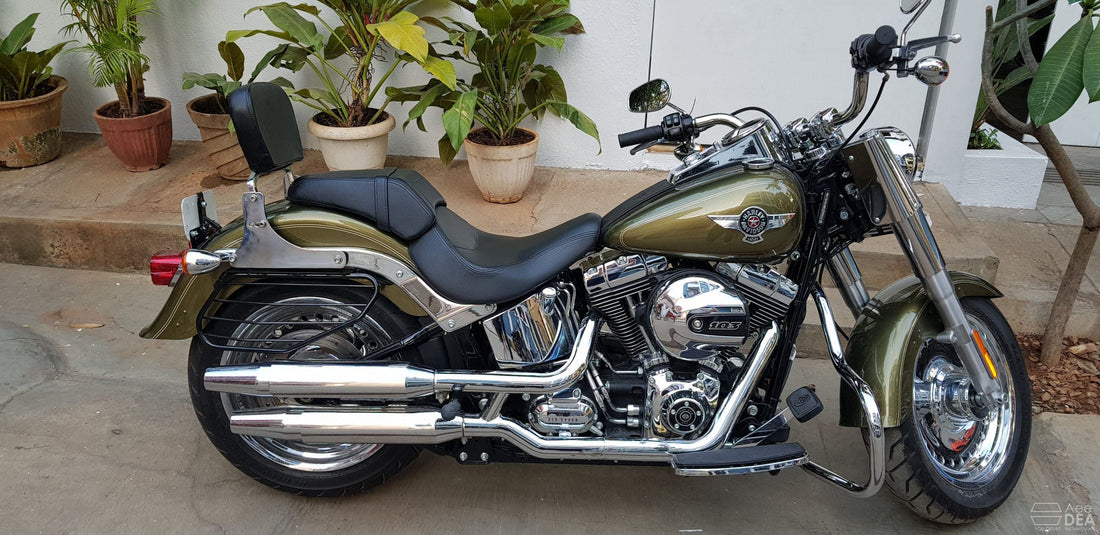 Side view of an olive-green cruiser motorcycle fitted with a chrome engine guard around the engine area