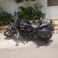 Full side view of a black Harley-Davidson motorcycle with windshield, rider backrest and side saddlebag