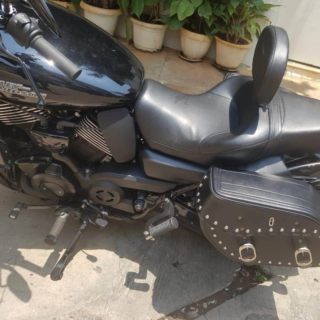 Side view of a black Harley-Davidson motorcycle fitted with a rider backrest and studded side saddlebag