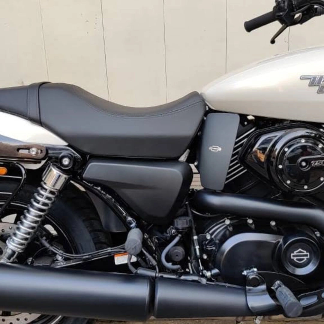 Close-up of a black heat deflector installed beside the motorcycle engine and rider foot controls