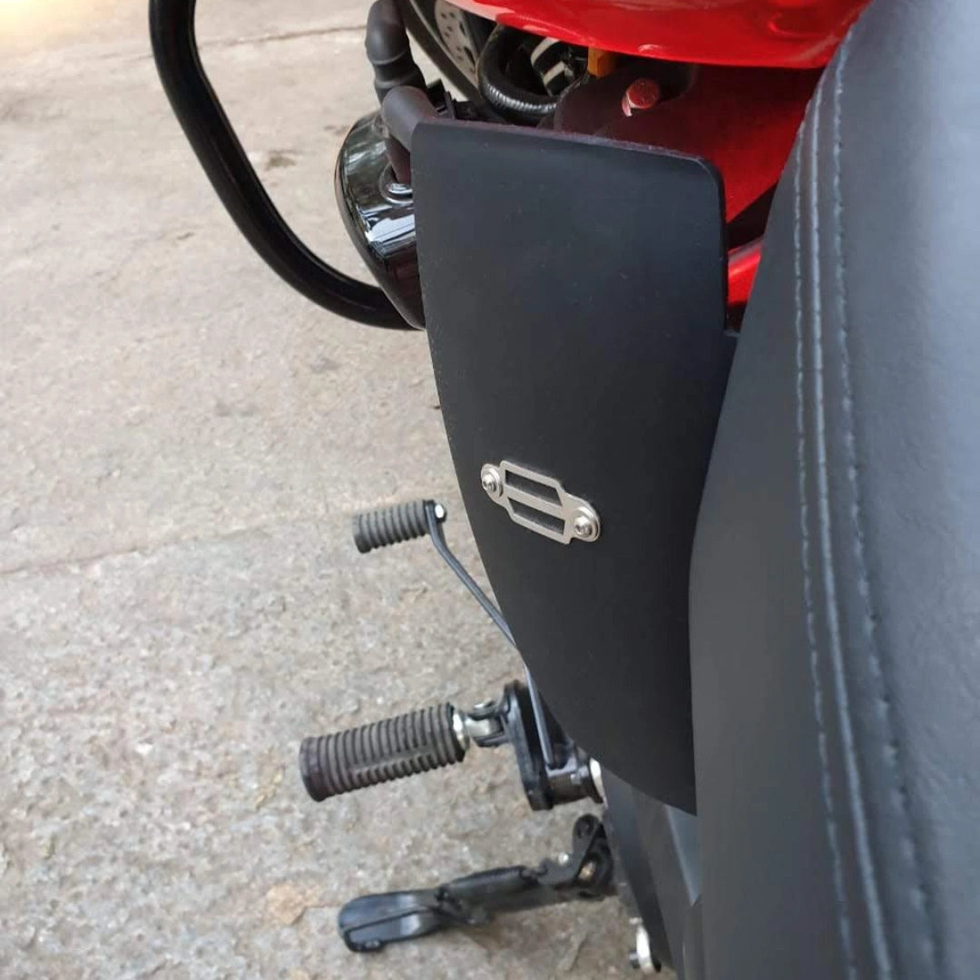 Close-up of a black motorcycle heat deflector mounted beside the engine near the rider foot controls