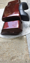 Pair of glossy maroon touring pannier boxes shown with a black backrest