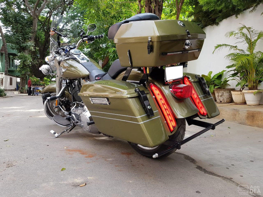 Olive-green cruiser motorcycle fitted with AeeDEA side panniers and a rear top box