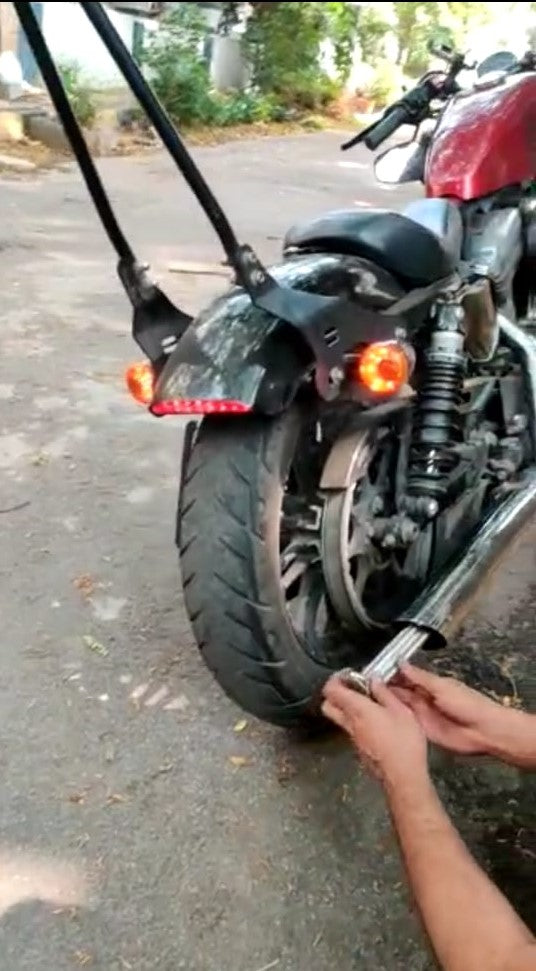 Hands fitting a DB killer insert into the exhaust outlet of a motorcycle